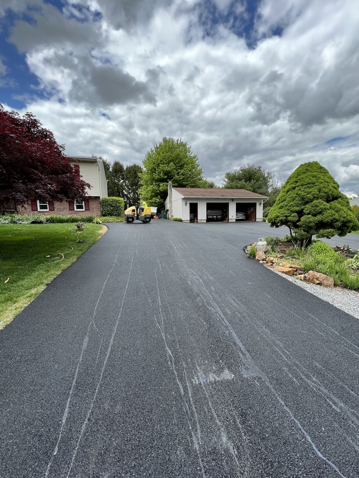 Wide asphalt driveway paved to detached garage